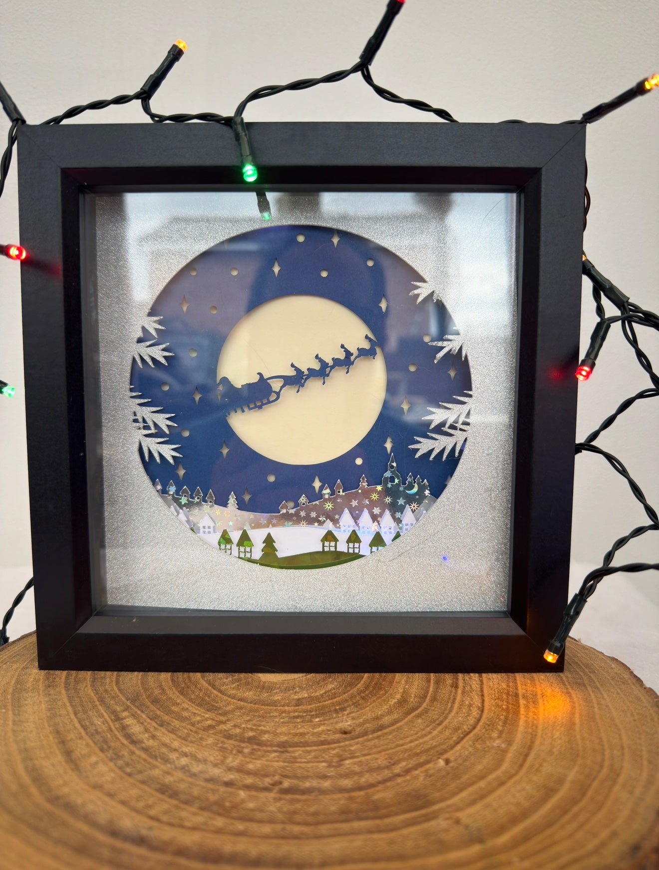 Framed artwork of a night scene with a full moon, trees, and a silhouette of a sleigh.
