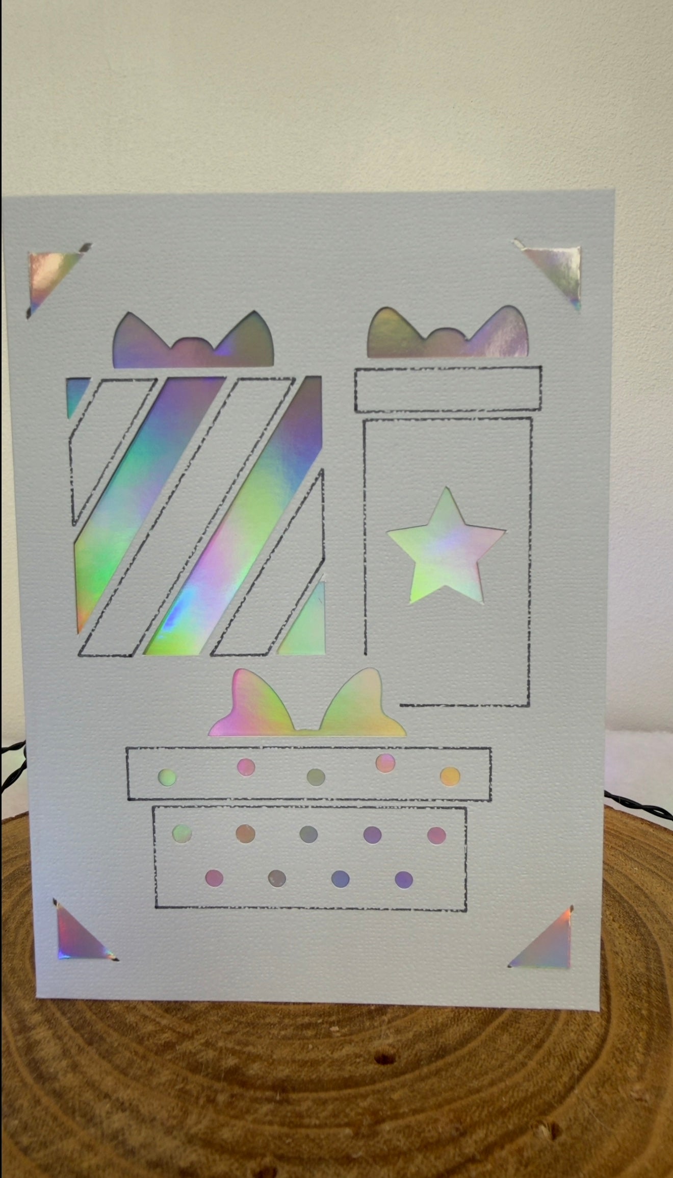 Holographic birthday card with presents and a star on a wooden surface