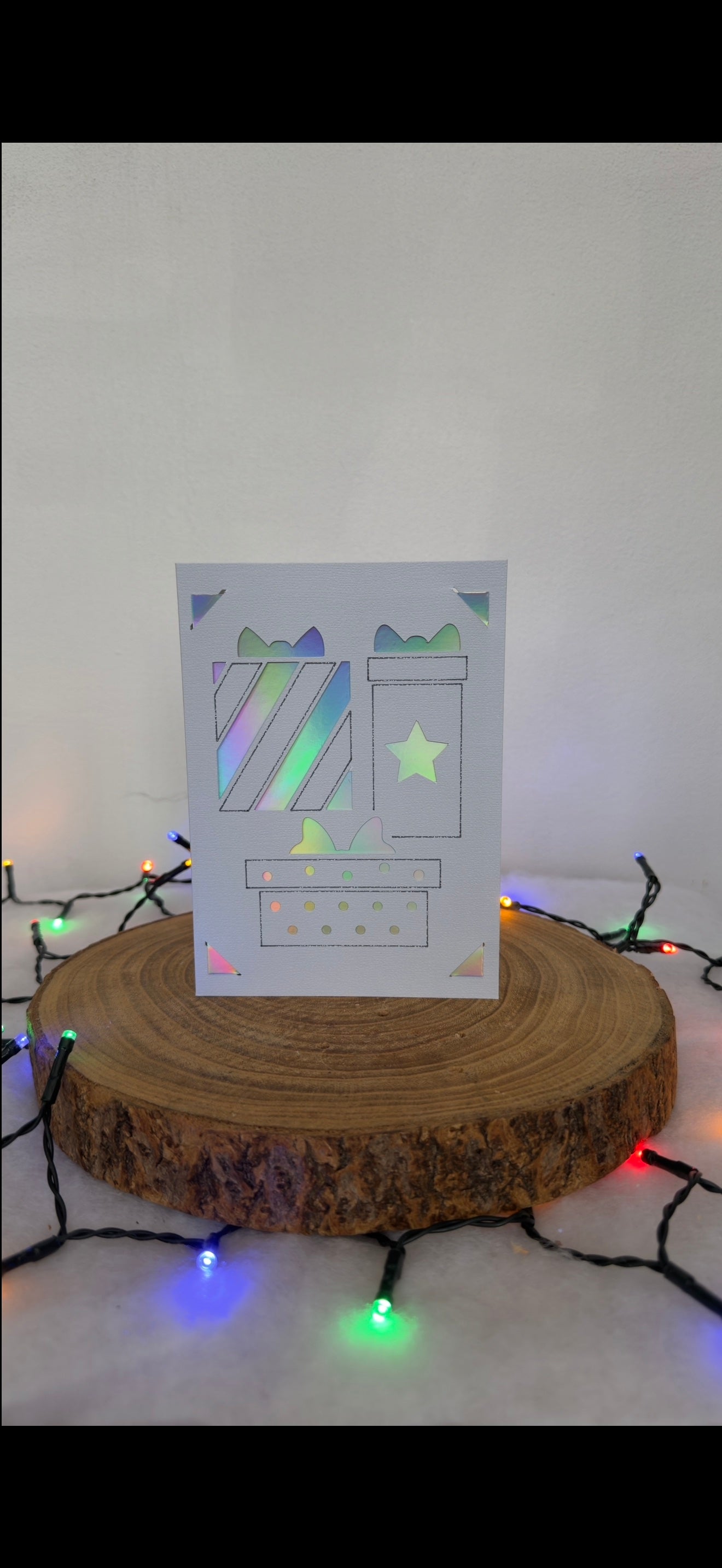 Card with festive design on a wooden stand with string lights in the background