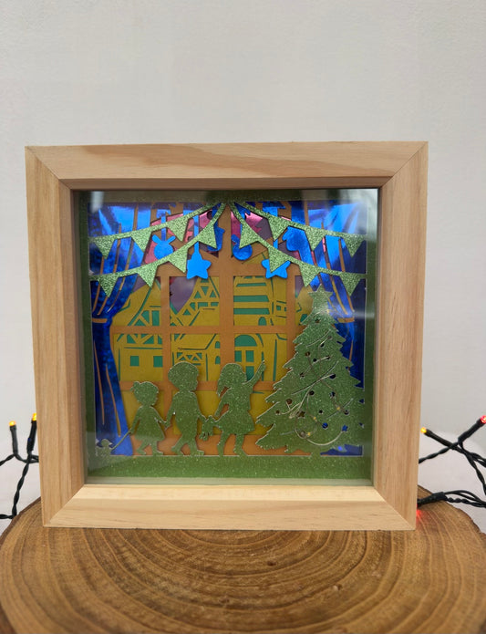 Framed paper cut art with a house, trees, and people on a white background