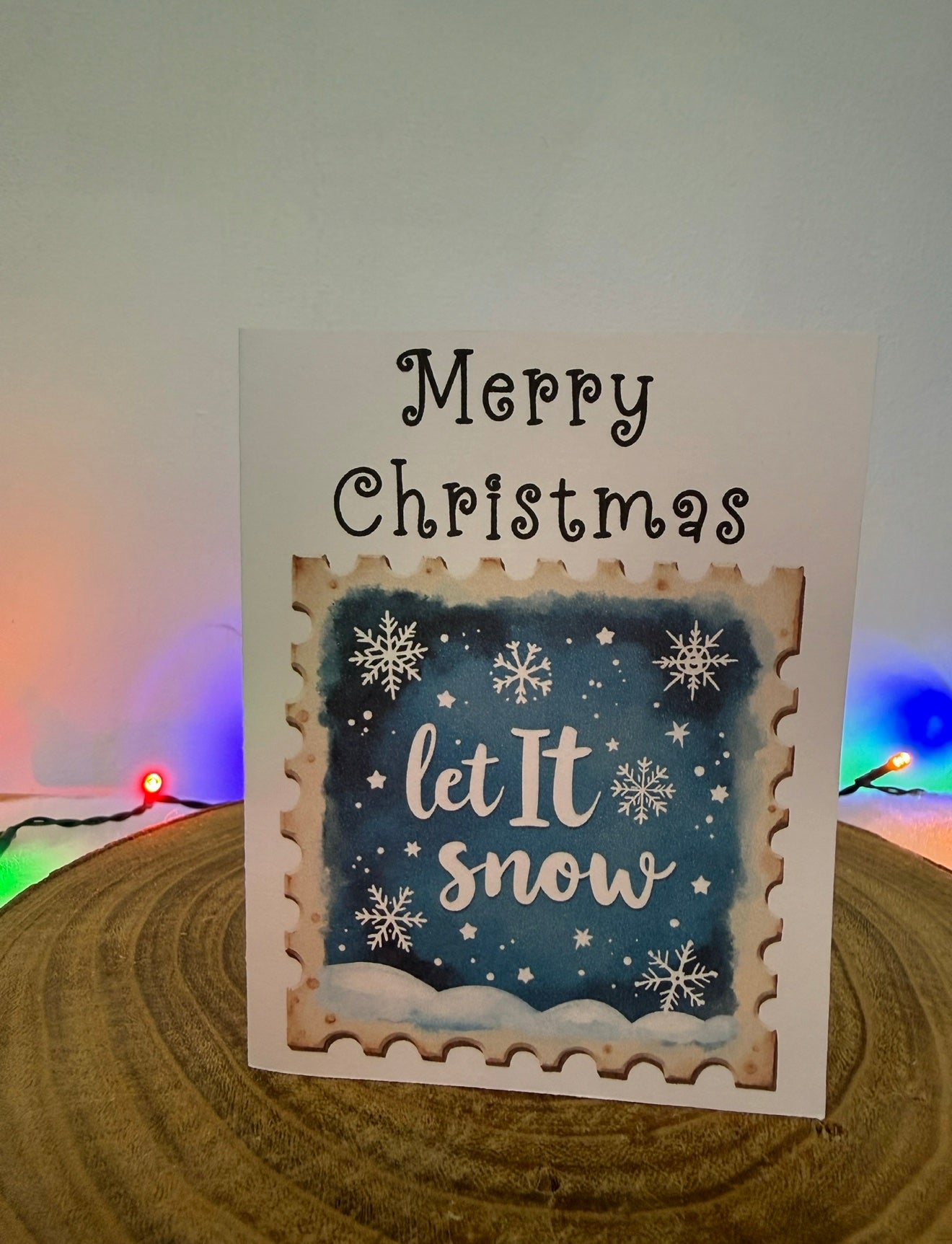 Christmas card with 'Merry Christmas, let it snow' text and snowflakes on a blue background.