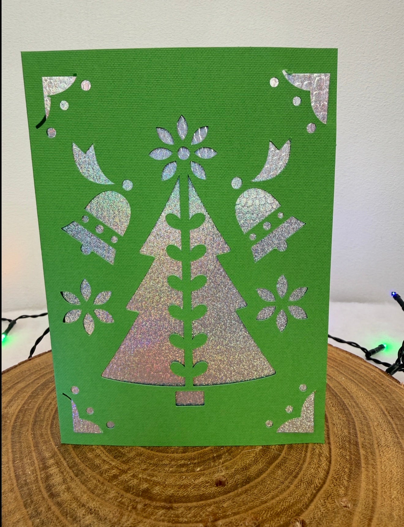 Green card with silver tree design on a wooden surface