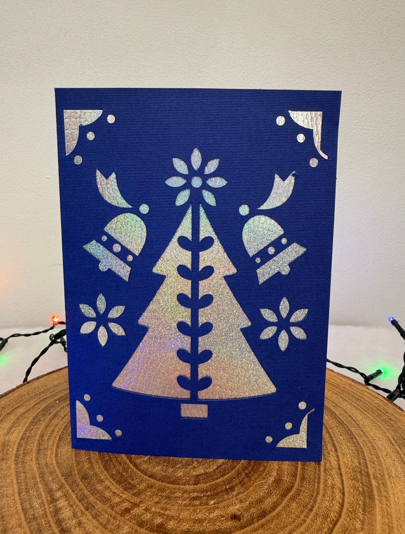 Blue card with white tree and snowflake design on a wooden surface