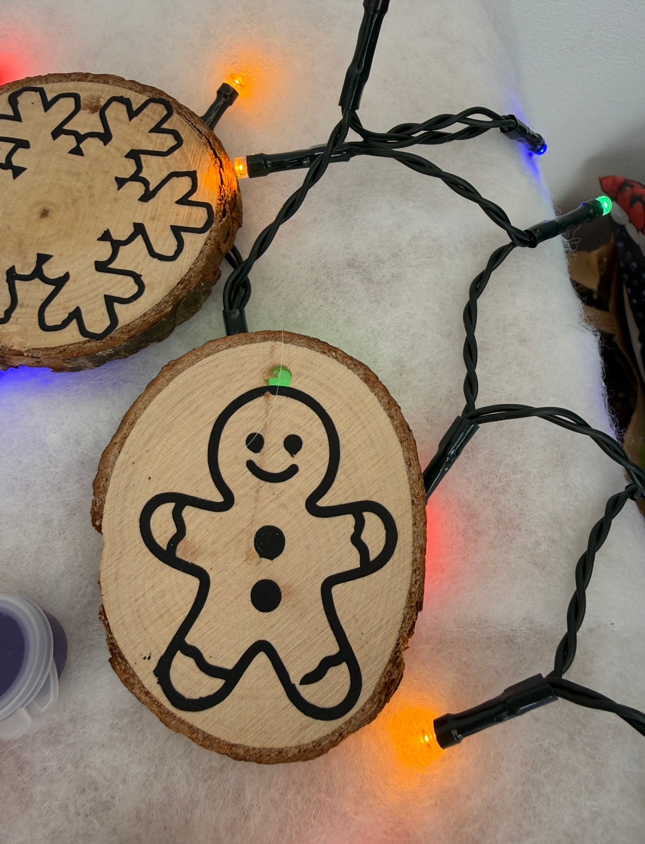 Wooden ornament with a gingerbread man design on a string of lights.