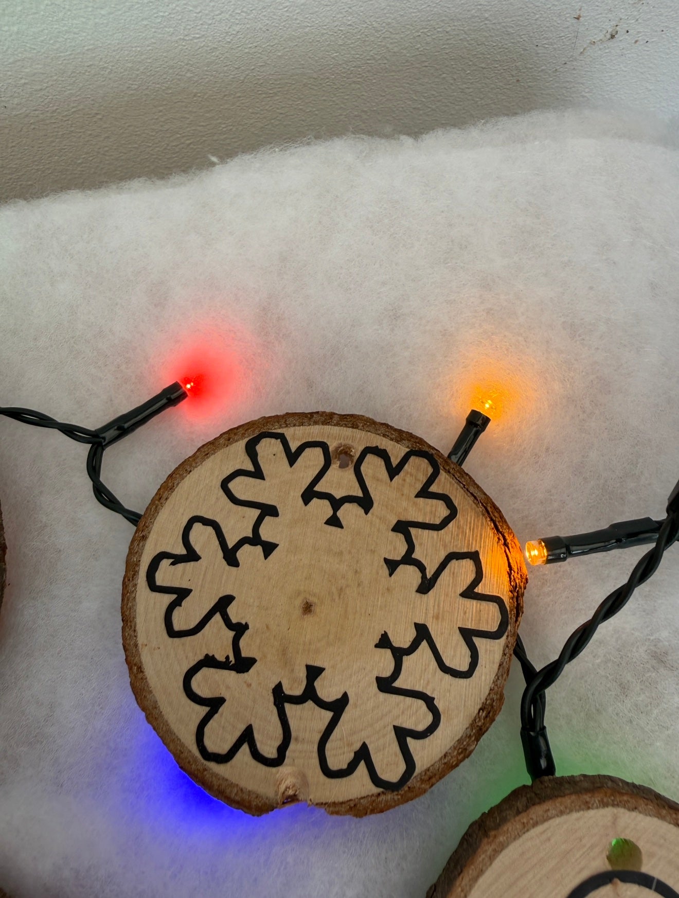 Wooden snowflake ornament with string lights on a white background