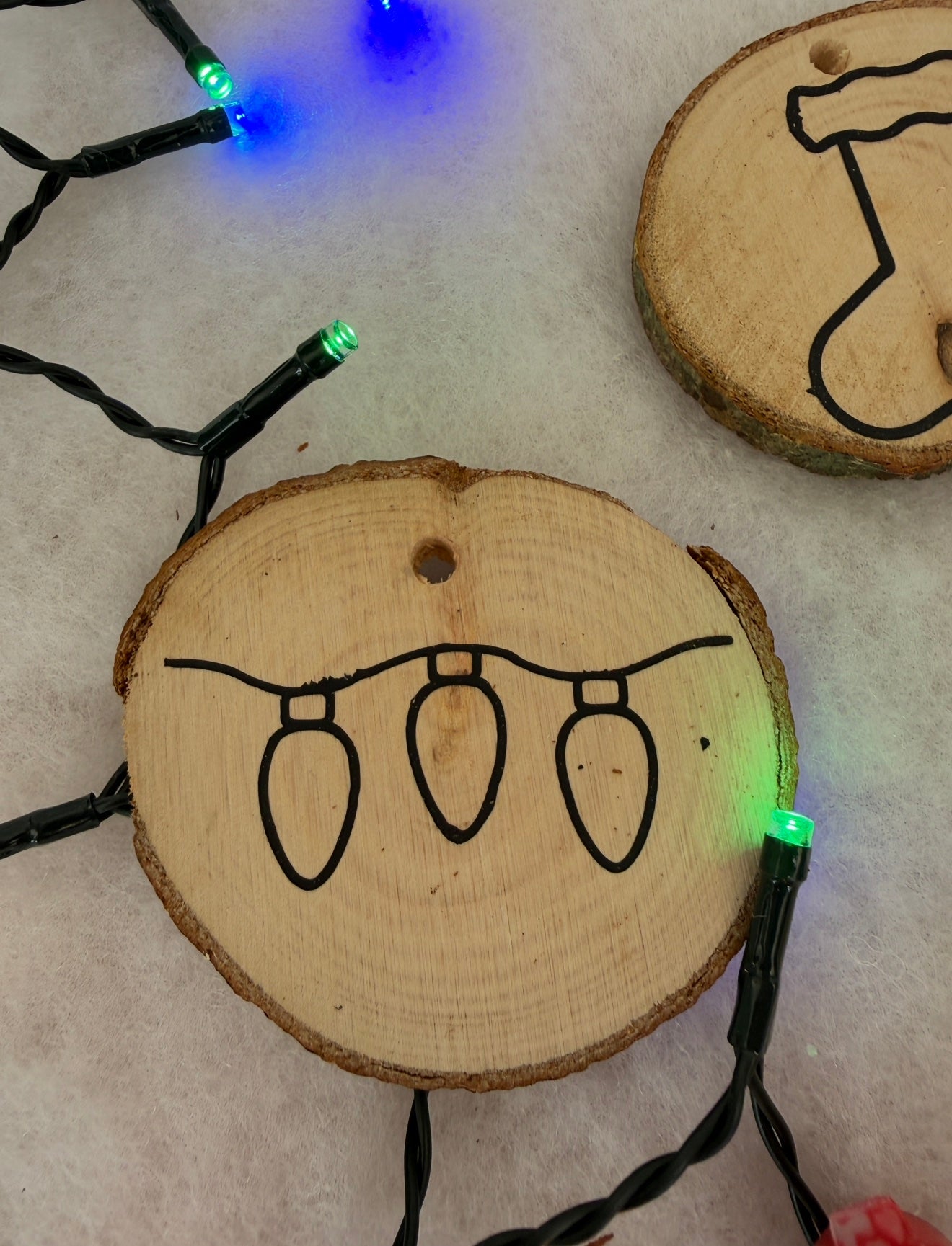 Wooden ornaments with Christmas light designs on a light background