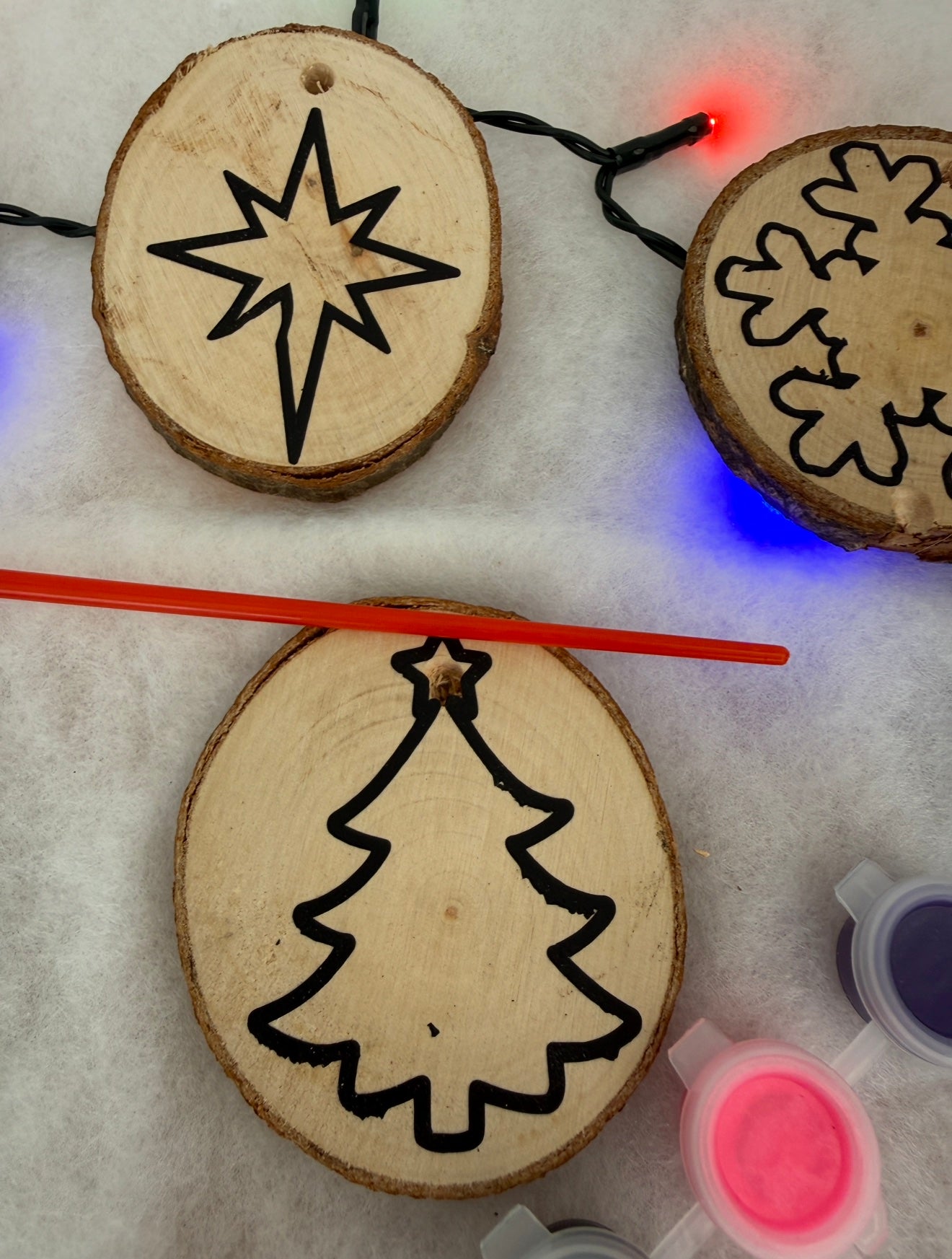 Wooden ornaments with star, tree, and snowflake designs on a light background.
