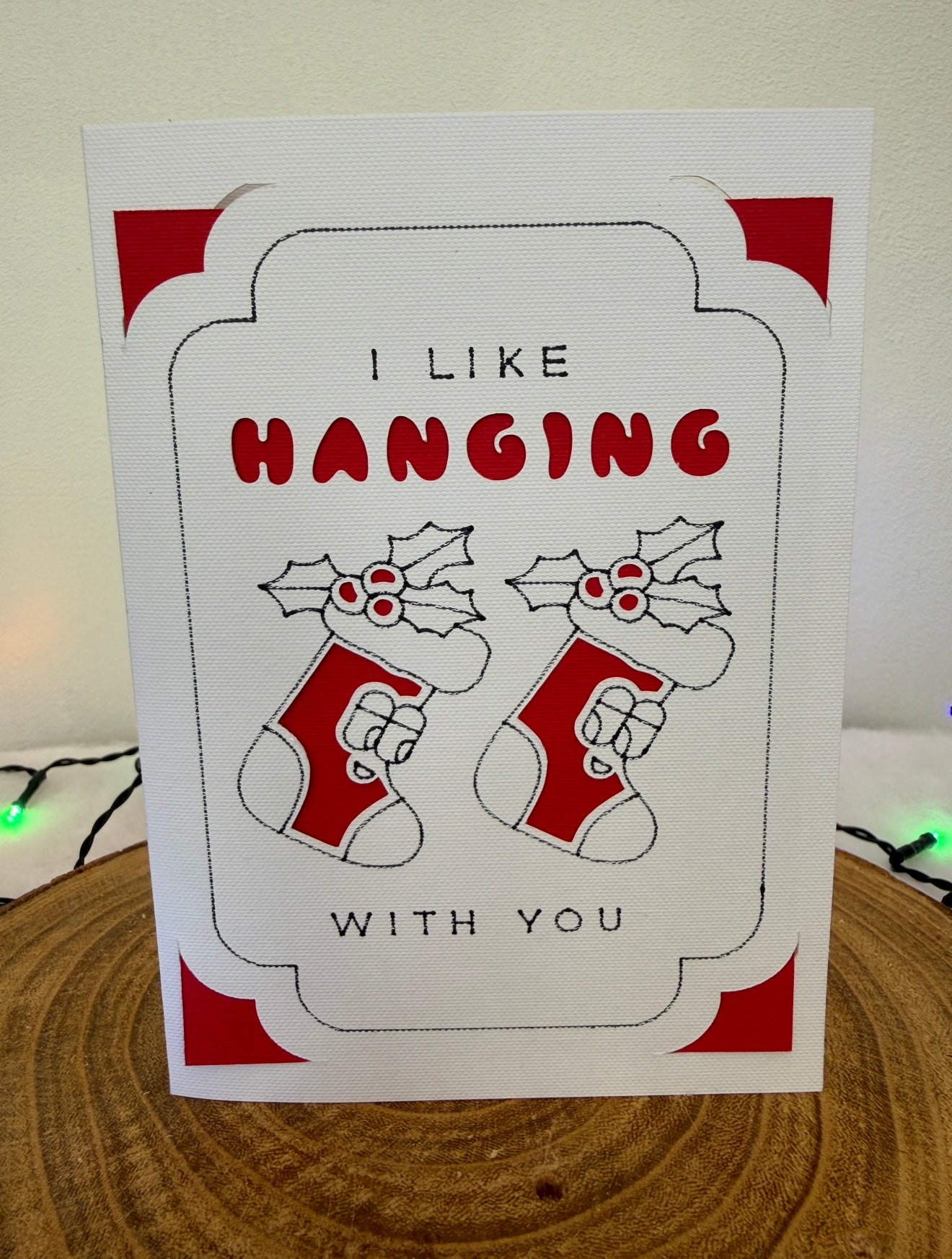Card with stockings and text 'I like hanging with you' on a wooden surface.