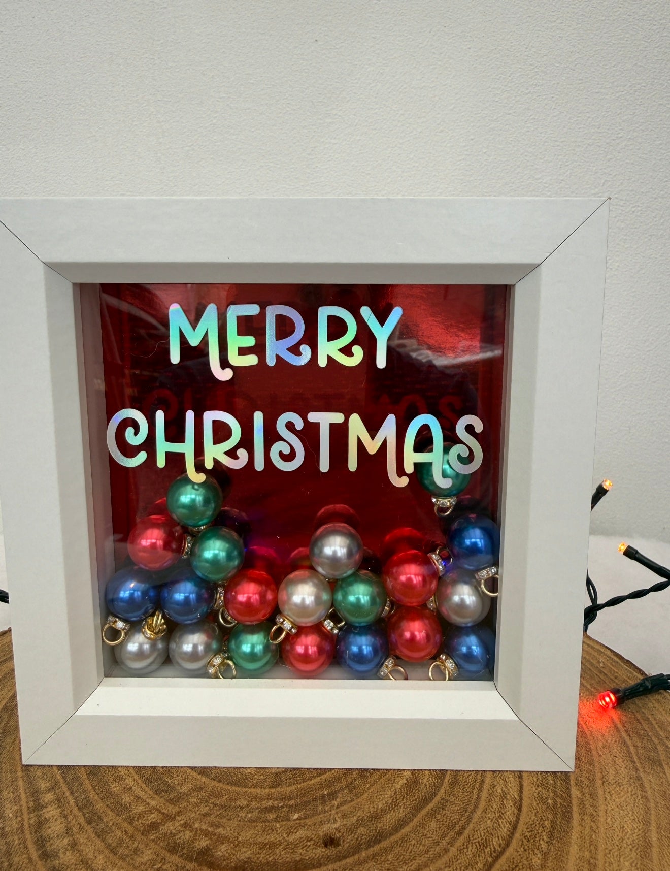 Decorative shadow box with colorful Christmas ornaments and 'Merry Christmas' text.